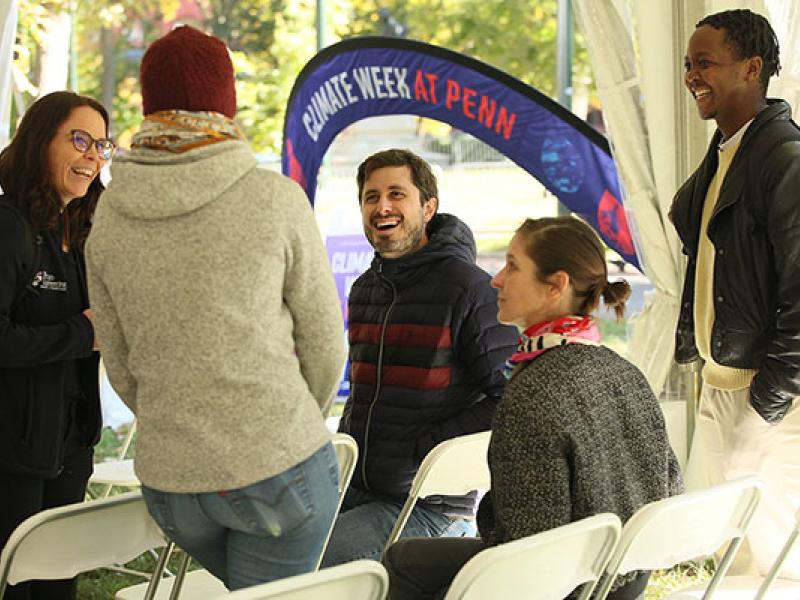 circle of five people talking near climate week banner