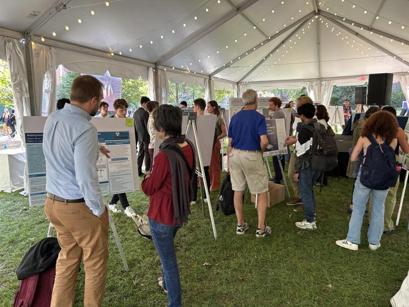 Attendees gathered in a tent, engaging with posters displayed around them.